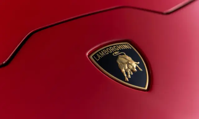 Złoty byk na czarnym tle z napisem "Lamborghini" - tak wygląda znaczek tej marki na czerwonej karoserii.