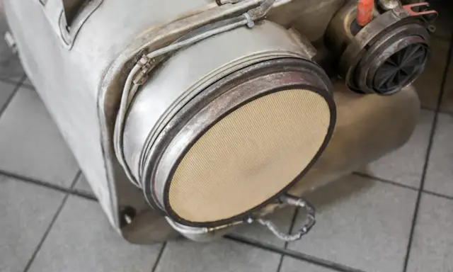 Element układu wydechowego, prawdopodobnie filtr DPF, gotowy do wypalania. Widoczny ceramiczny wkład.