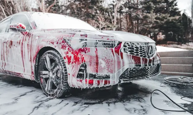 Czerwony samochód pokryty pianą, gotowy do mycia. Czy można myć auto w mrozie? To pytanie zadaje sobie wielu kierowców zimą.