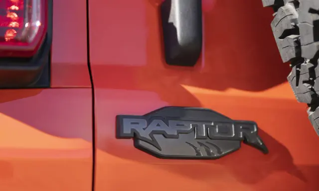 Pomarańczowy lakier lśni, a czarne, wyraziste logo "RAPTOR" z pazurami podkreśla jego dziką naturę.