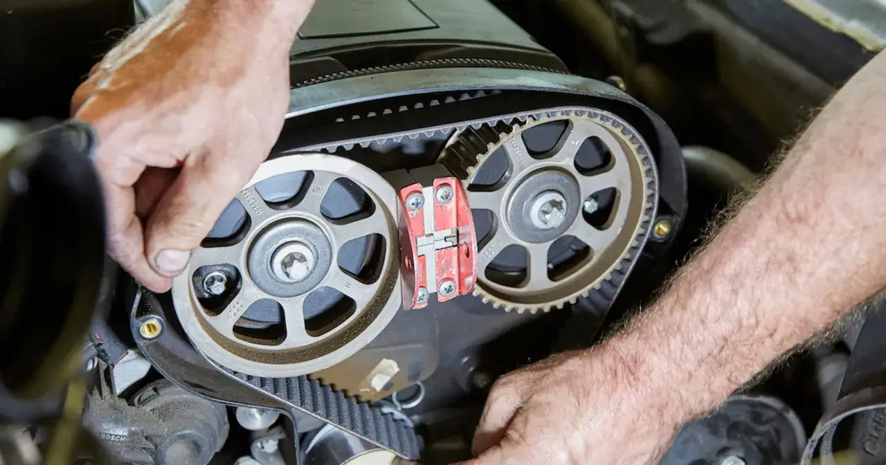 Mechanik precyzyjnie montuje nowy pasek podczas wymiany rozrządu. Widoczne koła zębate i napinacz.