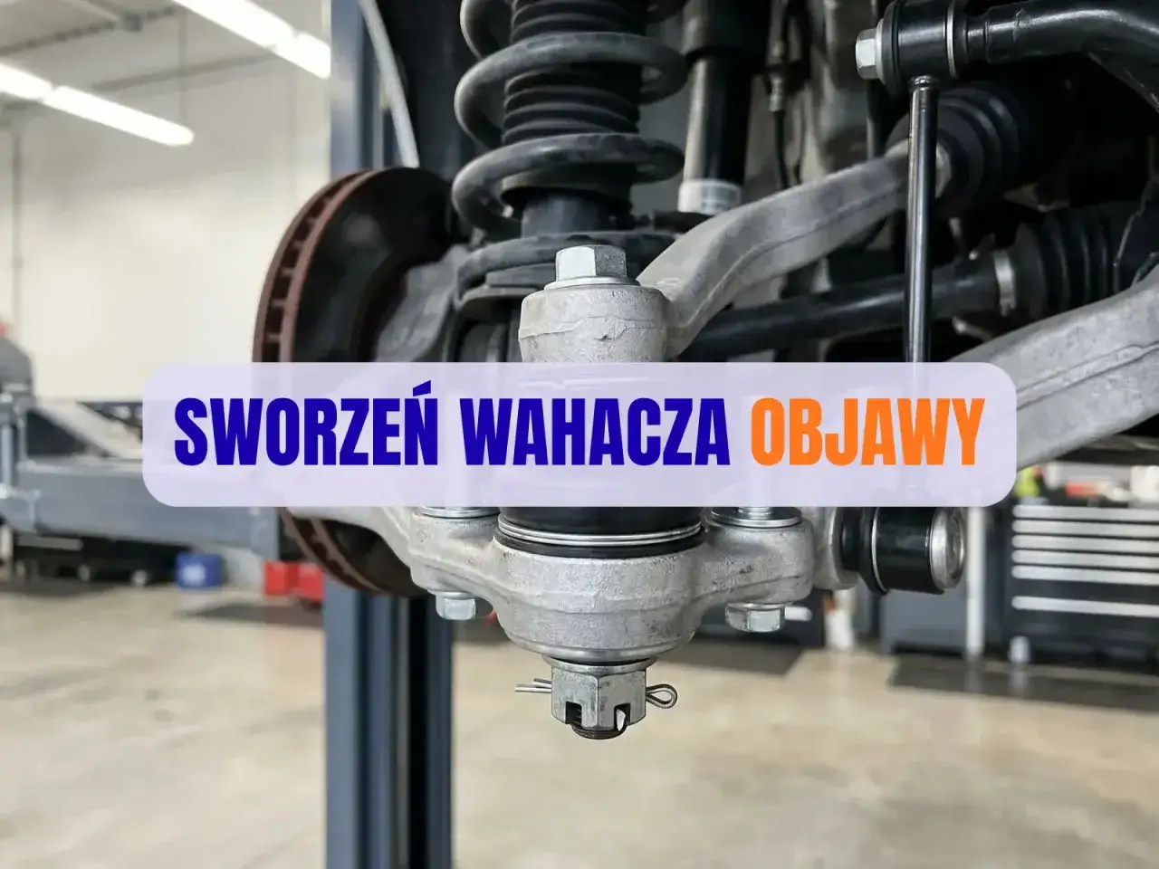 Widok na zawieszenie samochodu z widocznymi sworzeniami wahaczy. Tekst informuje o objawach zużycia sworznia wahacza.