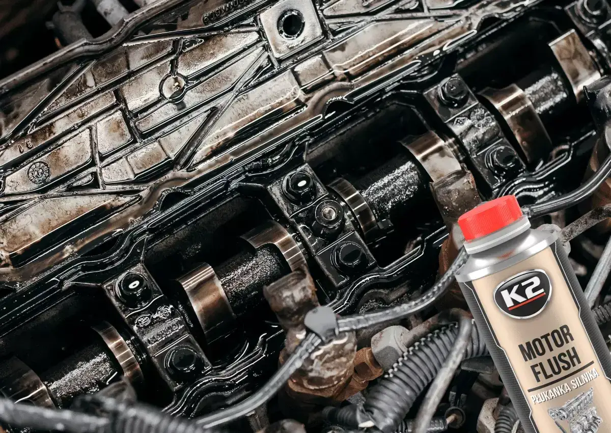 Zanieczyszczony silnik benzynowy i butelka K2 Motor Flush – najlepsza płukanka do silnika benzynowego, która przywróci mu czystość i moc.