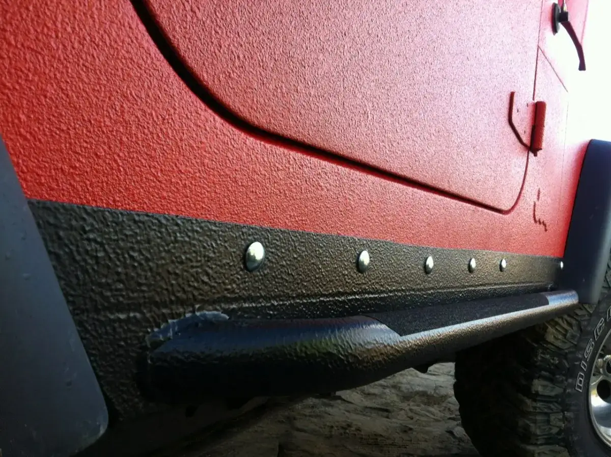 Czerwony Jeep po malowaniu Raptor. Solidne progi i błotniki chronią karoserię przed uszkodzeniami.