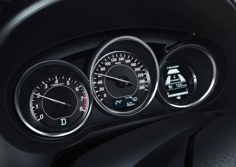 Deska rozdzielcza z obrotomierzem, prędkościomierzem i wyświetlaczem i-ELOOP. Widać falujące obroty silnika i prędkość 100 km/h.